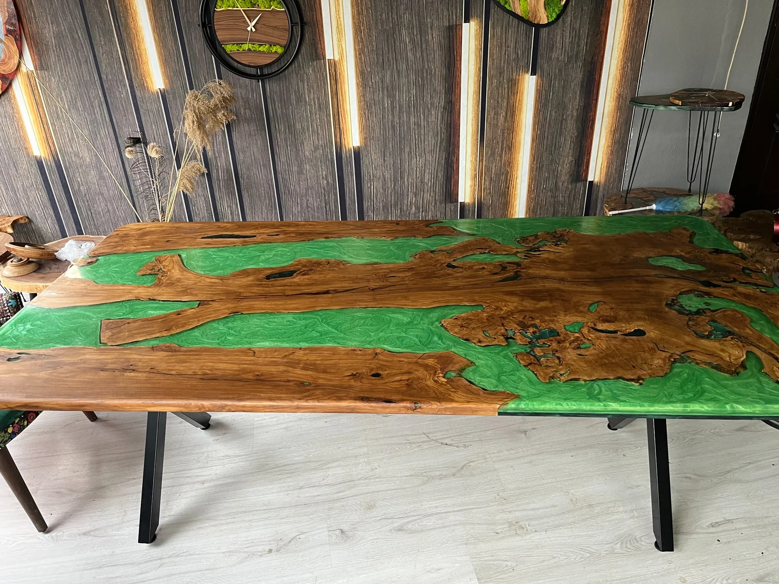 Green epoxy dining table with natural wood sections and black metal legs