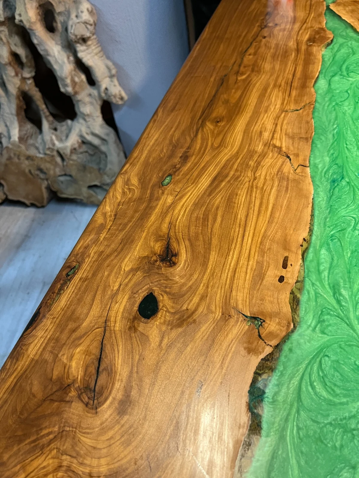 Close-up of golden wood grain and dark knots beside green epoxy