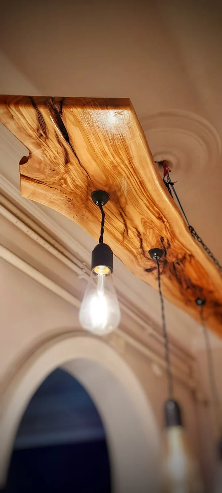 Close-up of golden olive wood grain, natural edge and black pendant socket