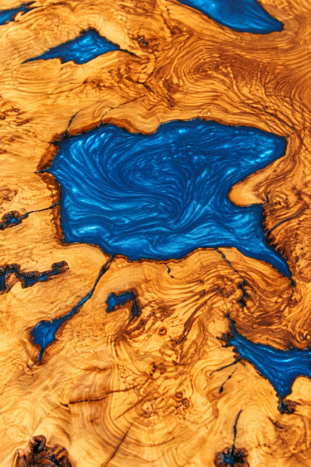 Digitally enhanced close-up reference of blue epoxy infill and golden olive wood grain