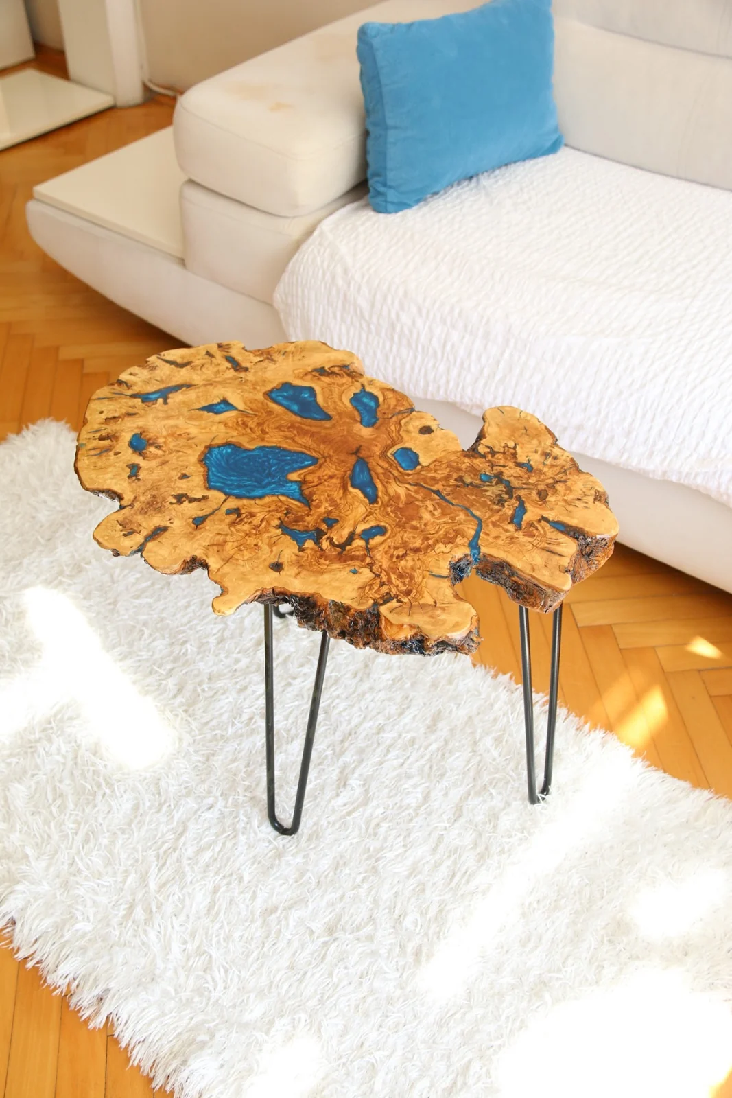 Olive wood live edge coffee table with blue epoxy-filled openings and black hairpin legs