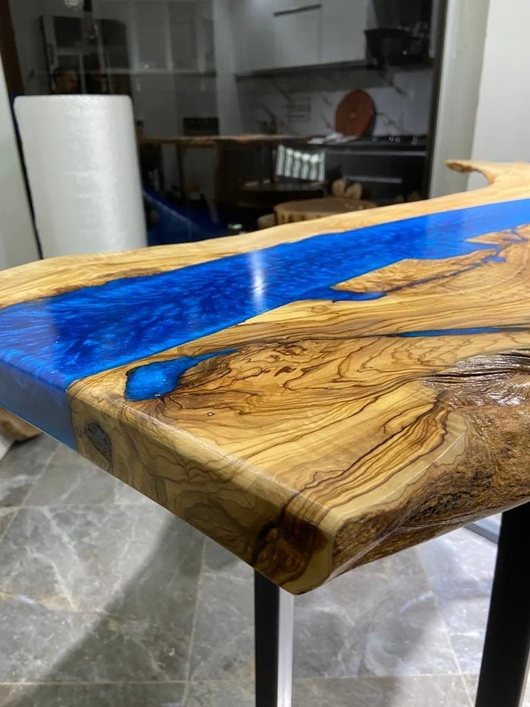 Close-up of olive wood grain and vivid blue epoxy at the end of the tabletop
