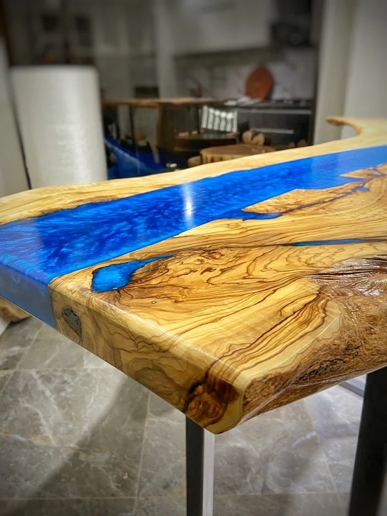 Natural olive wood grain beside the blue resin river on the console tabletop