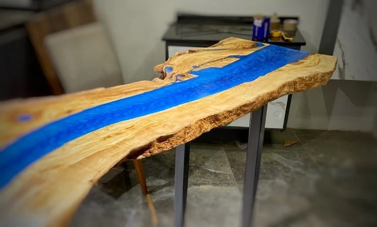 Full curved olive wood tabletop with blue epoxy river and black rectangular legs