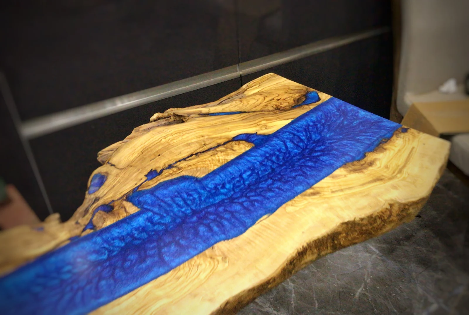 Detail of blue epoxy river and irregular natural olive wood edge
