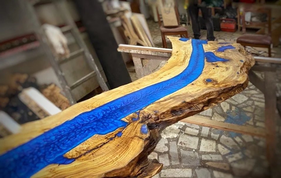 Angled workshop view of the blue epoxy river and natural olive wood outline