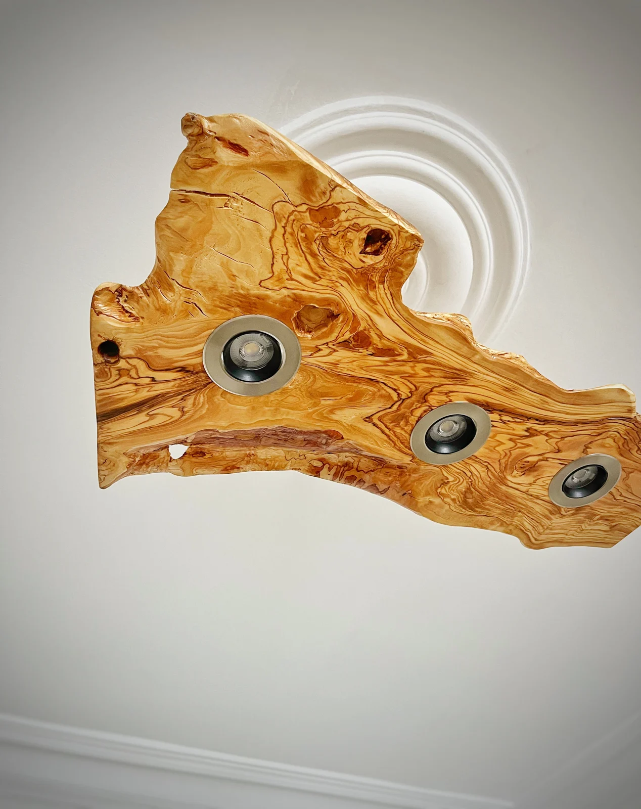 Angled detail of the live edge olive wood slab and three inset lights