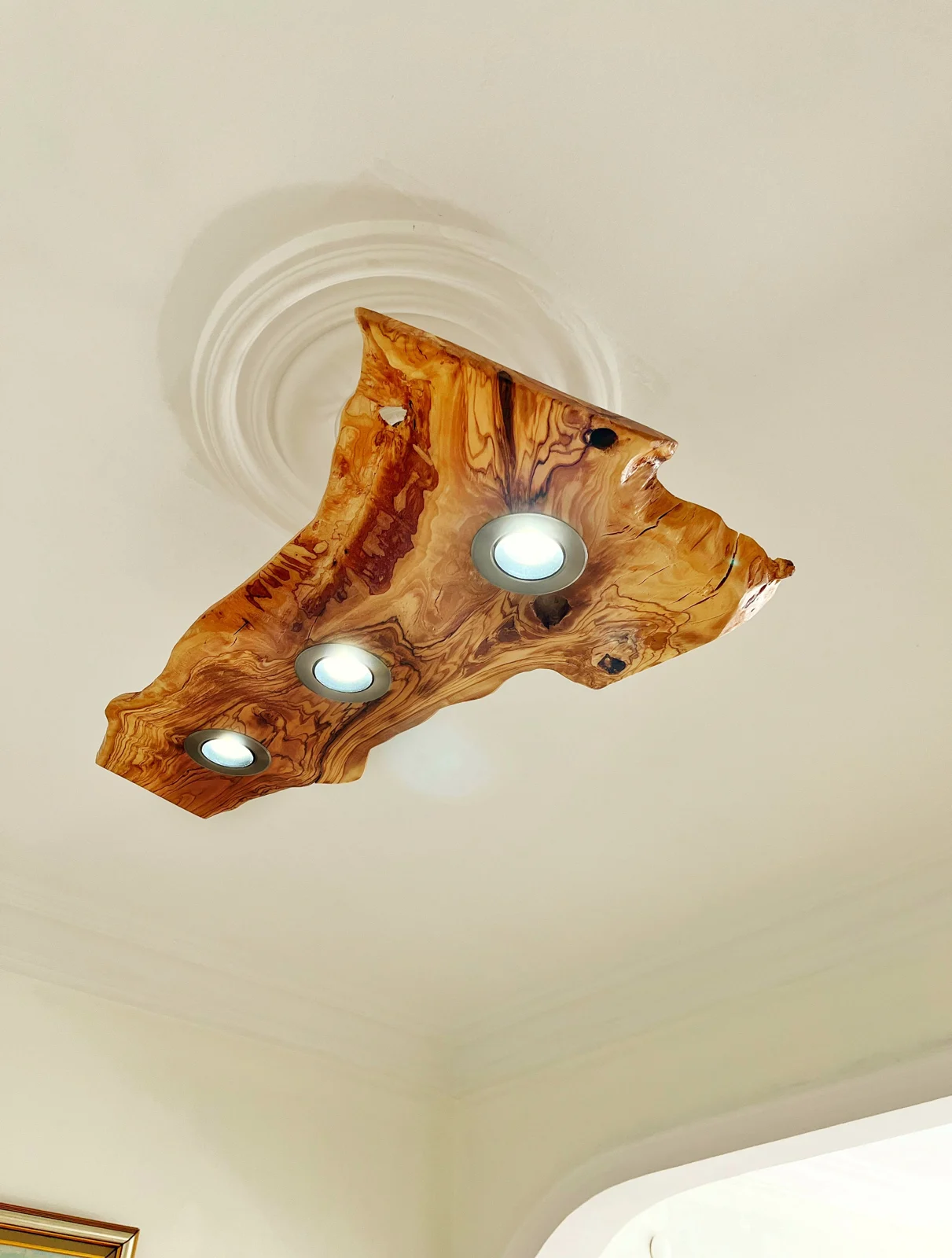 Olive wood ceiling light with three spotlights switched on in a room