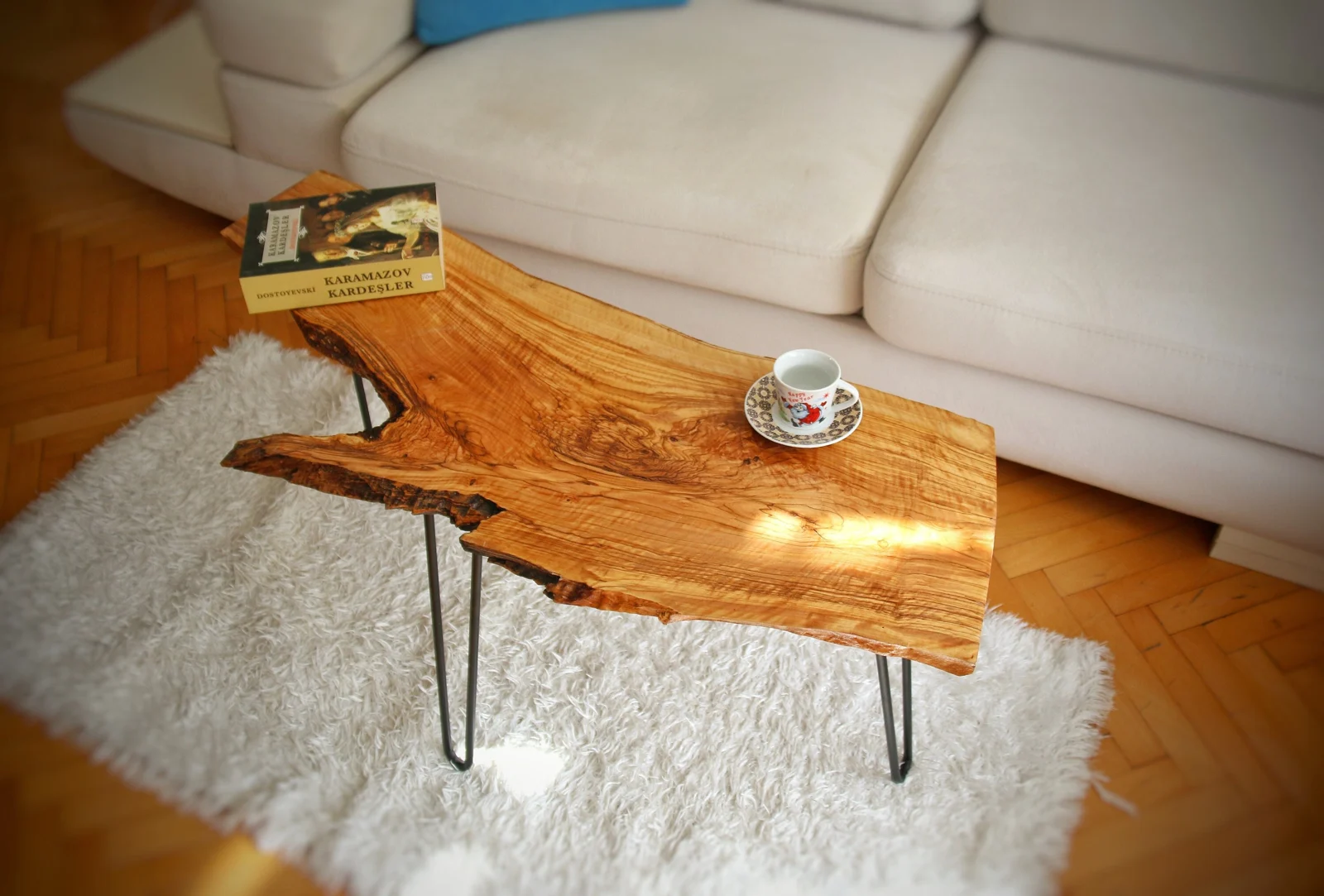 Olive wood live edge coffee table with black hairpin legs beside a cream sofa