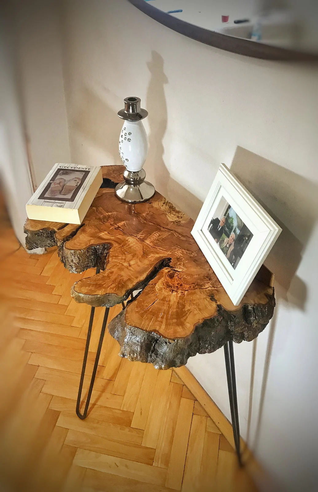 Natural olive slab console with expressive grain and irregular edge in a furnished room