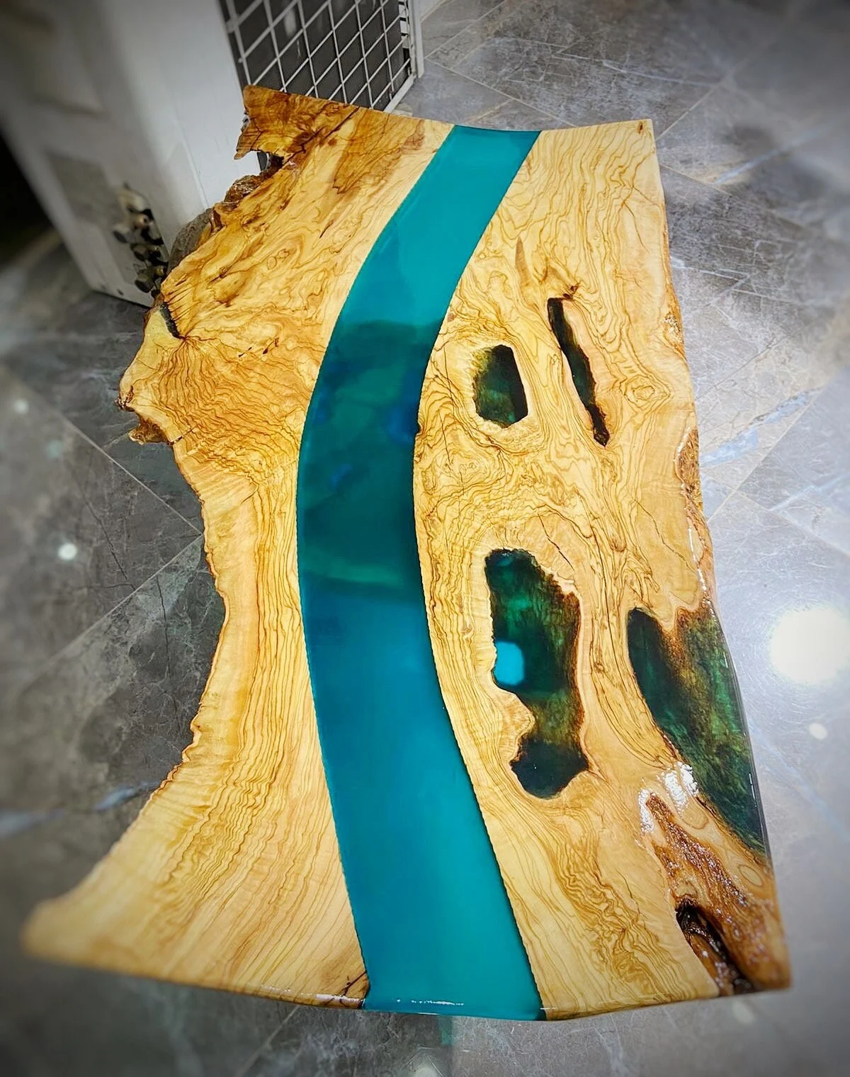 Olive wood live edge console tabletop with a blue epoxy river in the workshop