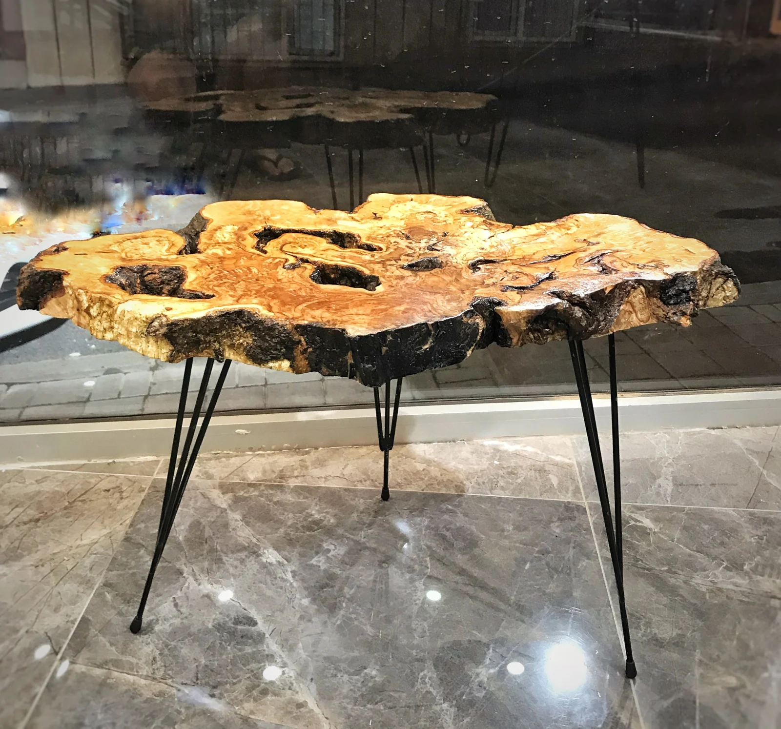 Angled view of the thick olive wood tabletop and black hairpin legs