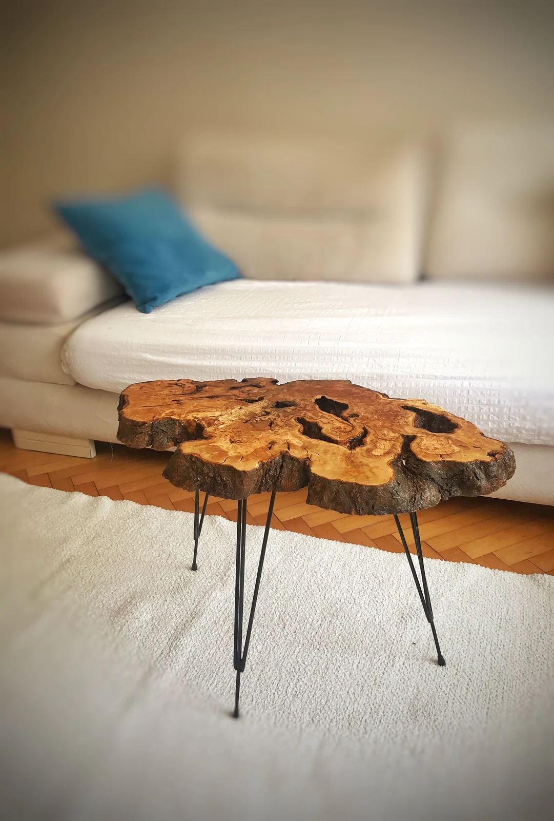 Front view of the olive wood coffee table beside a sofa with blue cushions