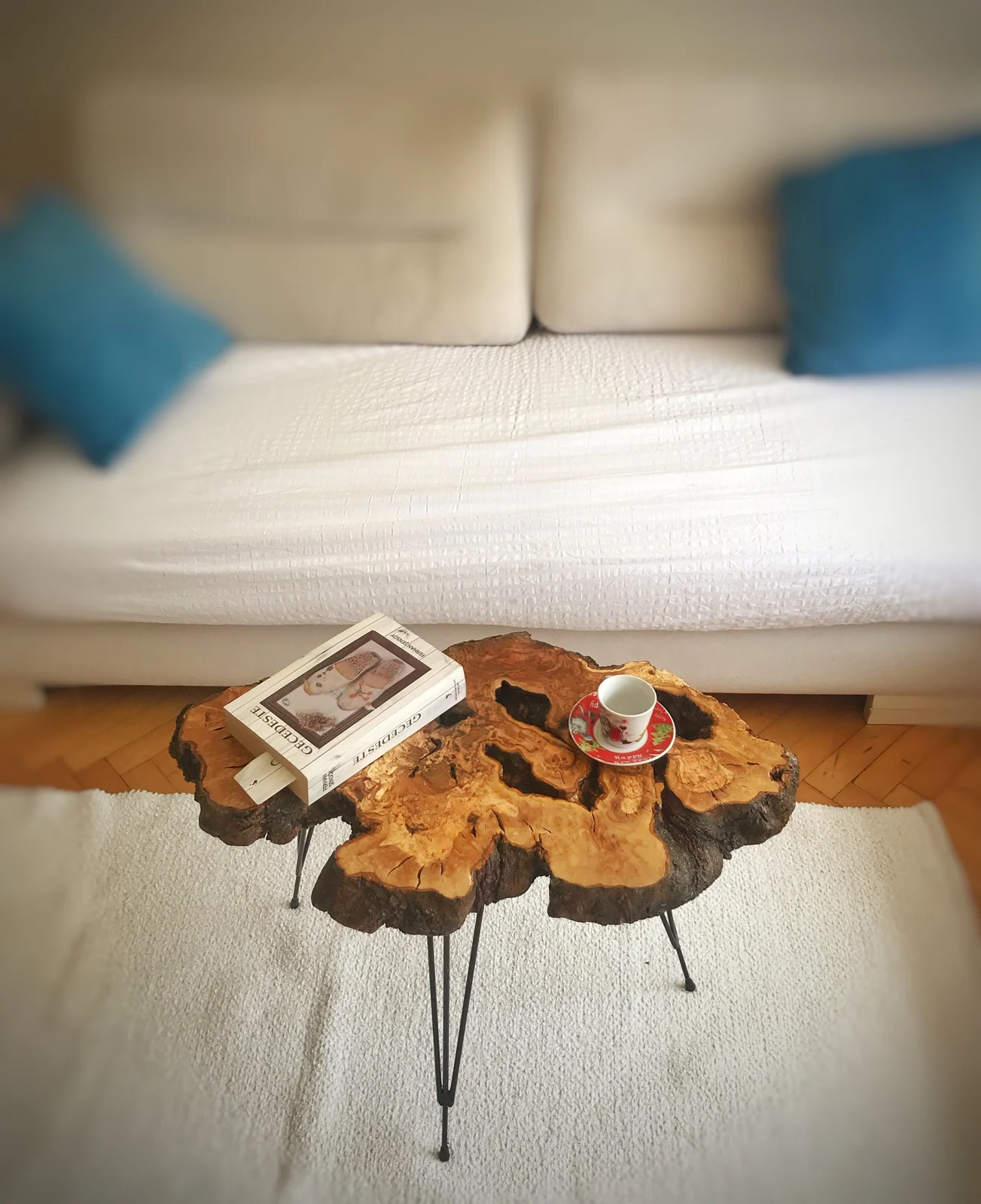 Olive wood slab coffee table styled with a book and cup beside a sofa