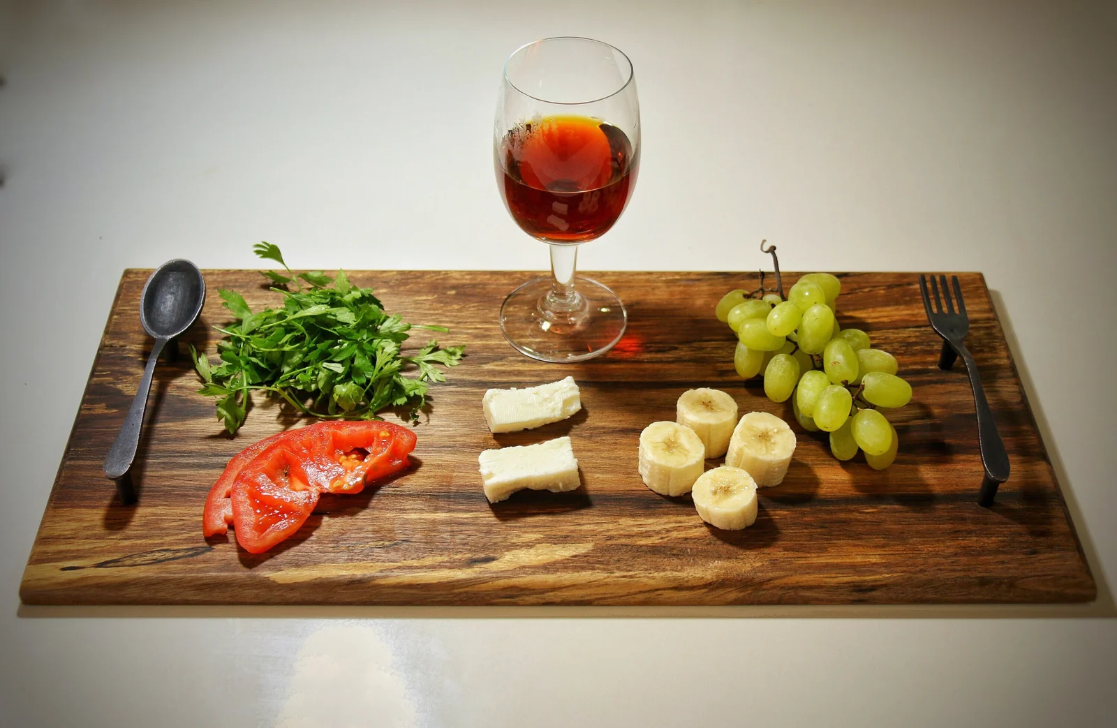 Walnut live edge serving board styled with cheese, fruit and a glass of wine
